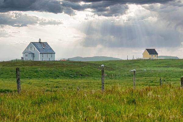 three houses are sitting on top of a grassy hill .