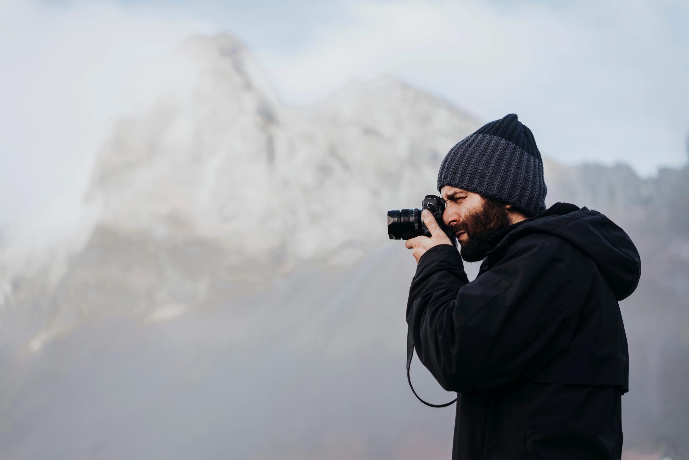 Turista con una camar delante de una montaña en Islandia