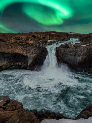 the aurora borealis is shining over a waterfall in iceland at Aldeyjarfoss.