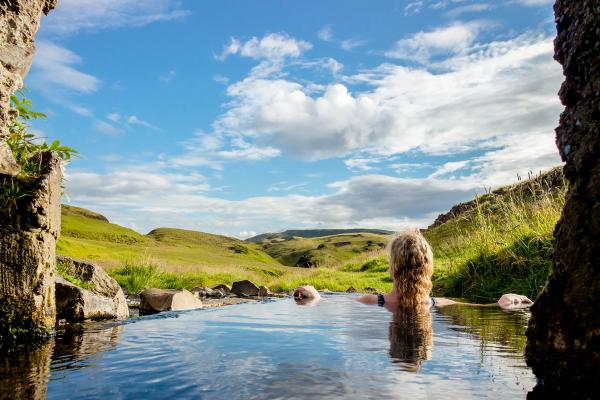 una mujer está nadando en una piscina de agua en medio de un campo.
