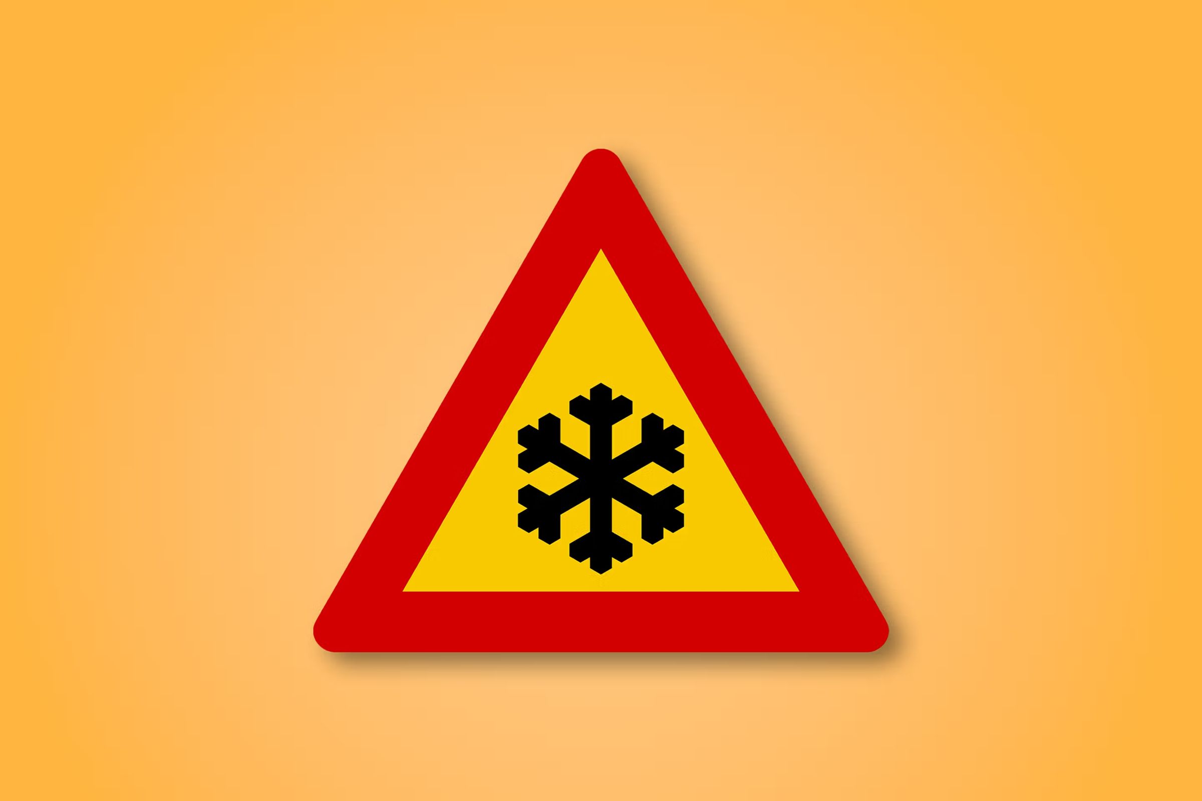 a yellow and red triangle sign with a snowflake on it .
