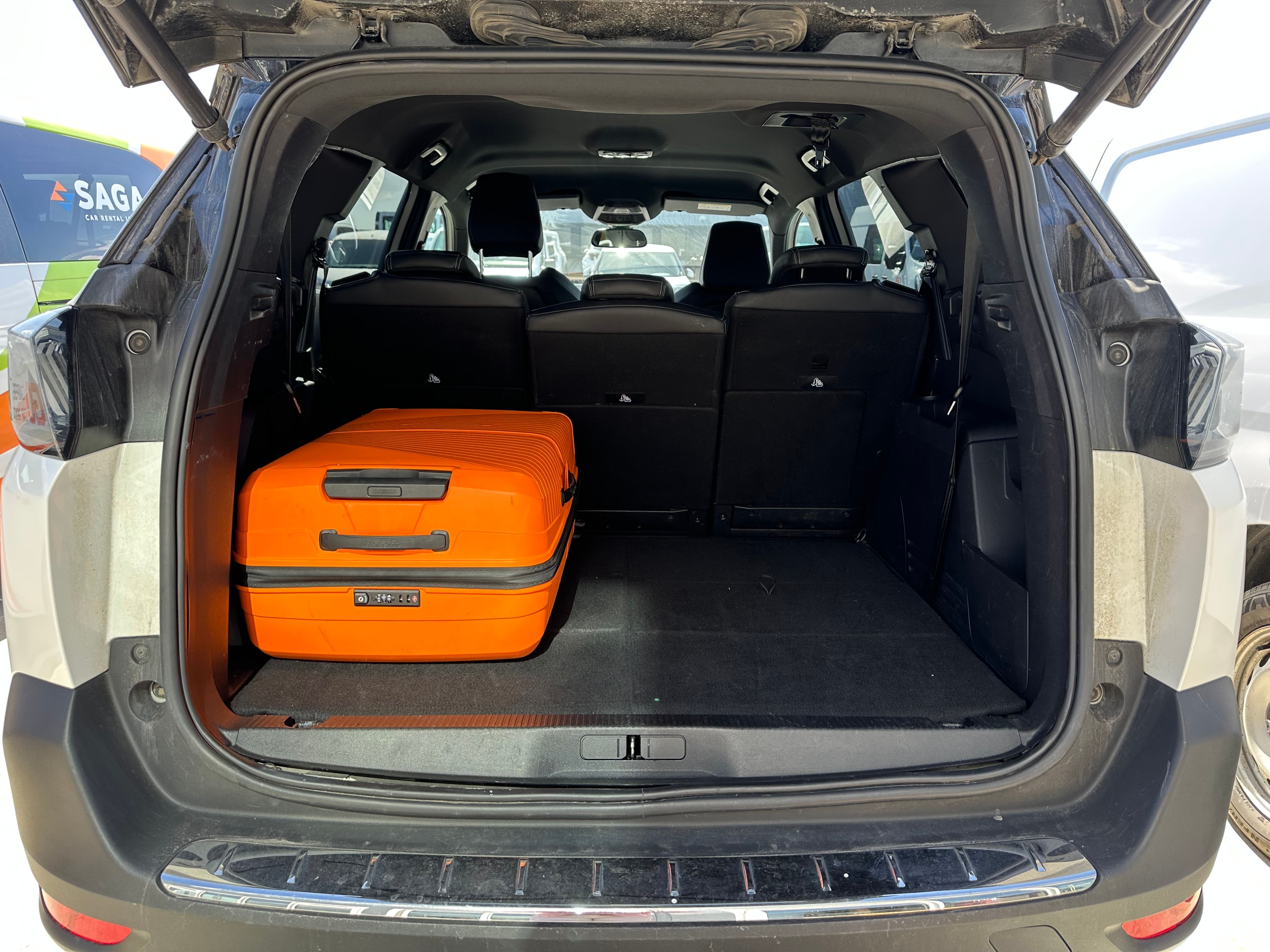 An open car trunk with an orange suitcase on the left, leaving ample empty space.