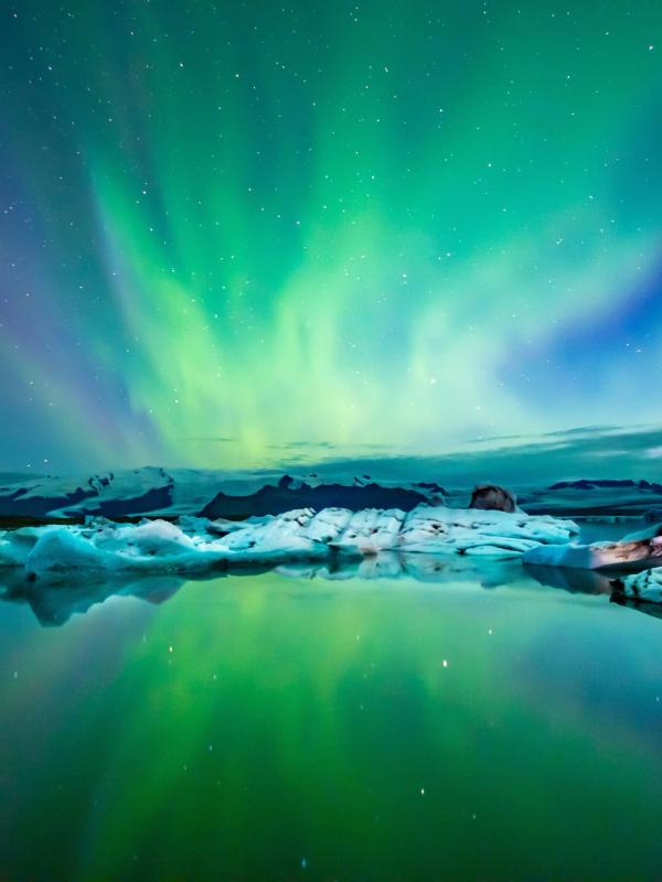the aurora borealis is reflected in the water of a lake .