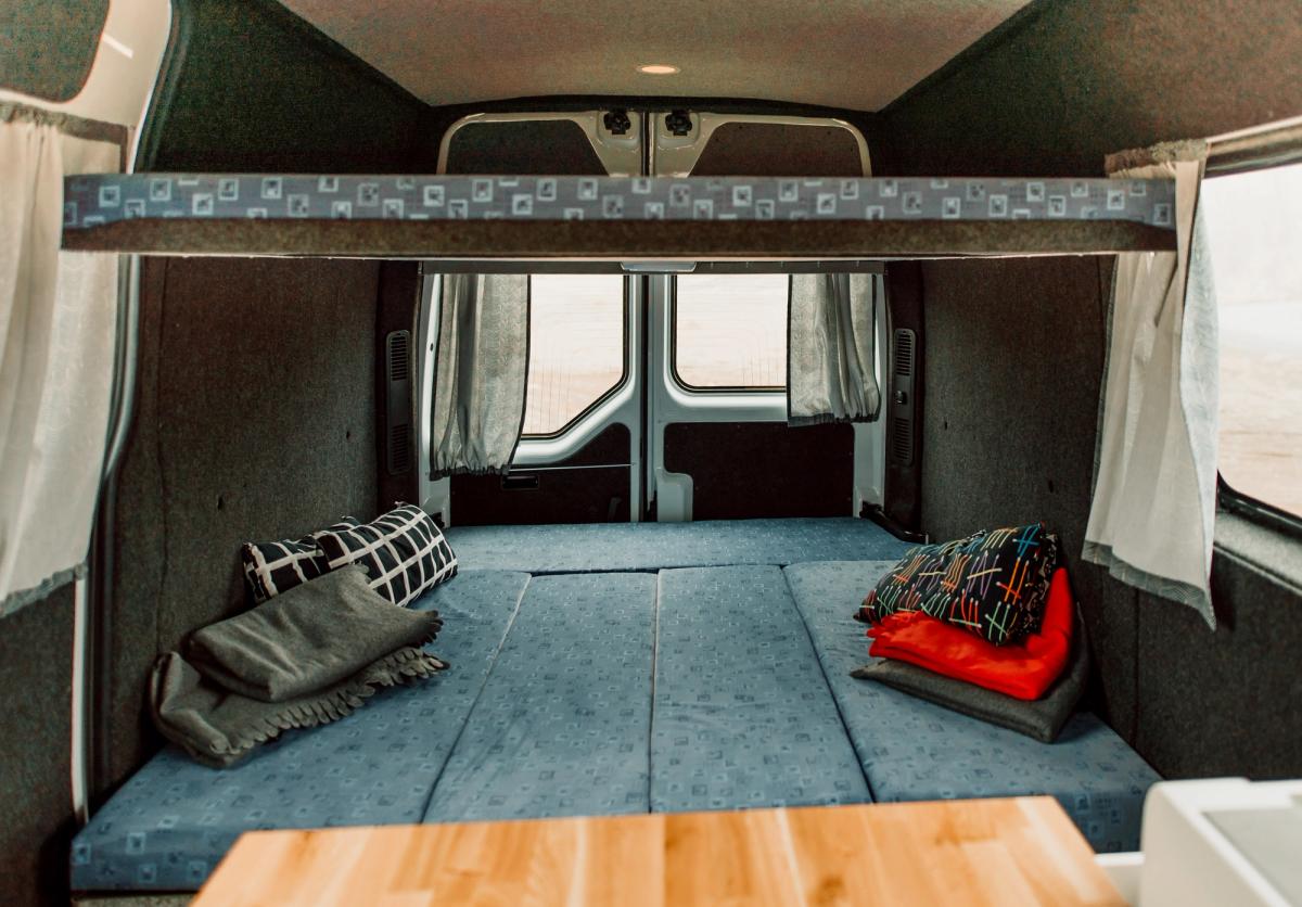 Unteres Bett mit Kissen unterhalb des oberen Betts in einem großen, preisgünstigen Camper für 5 Personen