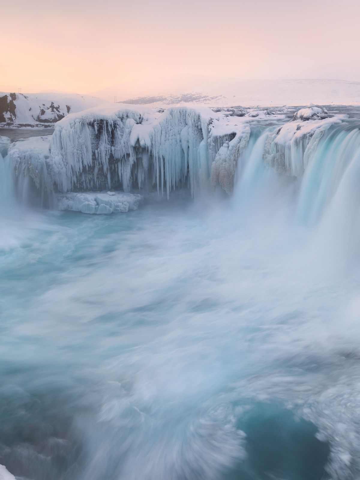 a waterfall is surrounded by ice and snow in the winter .