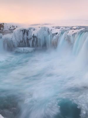una cascada está rodeada de hielo y nieve en invierno .