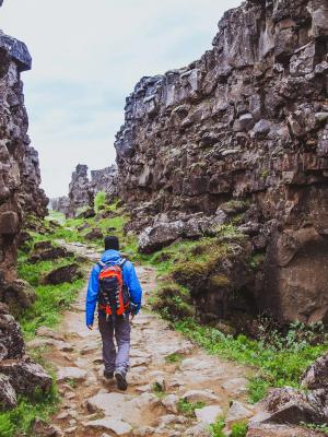 a man with a backpack is walking down a rocky path .
