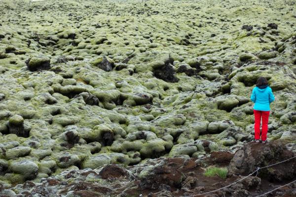 Mujer en frente de un campo de lava cubierto de musgo