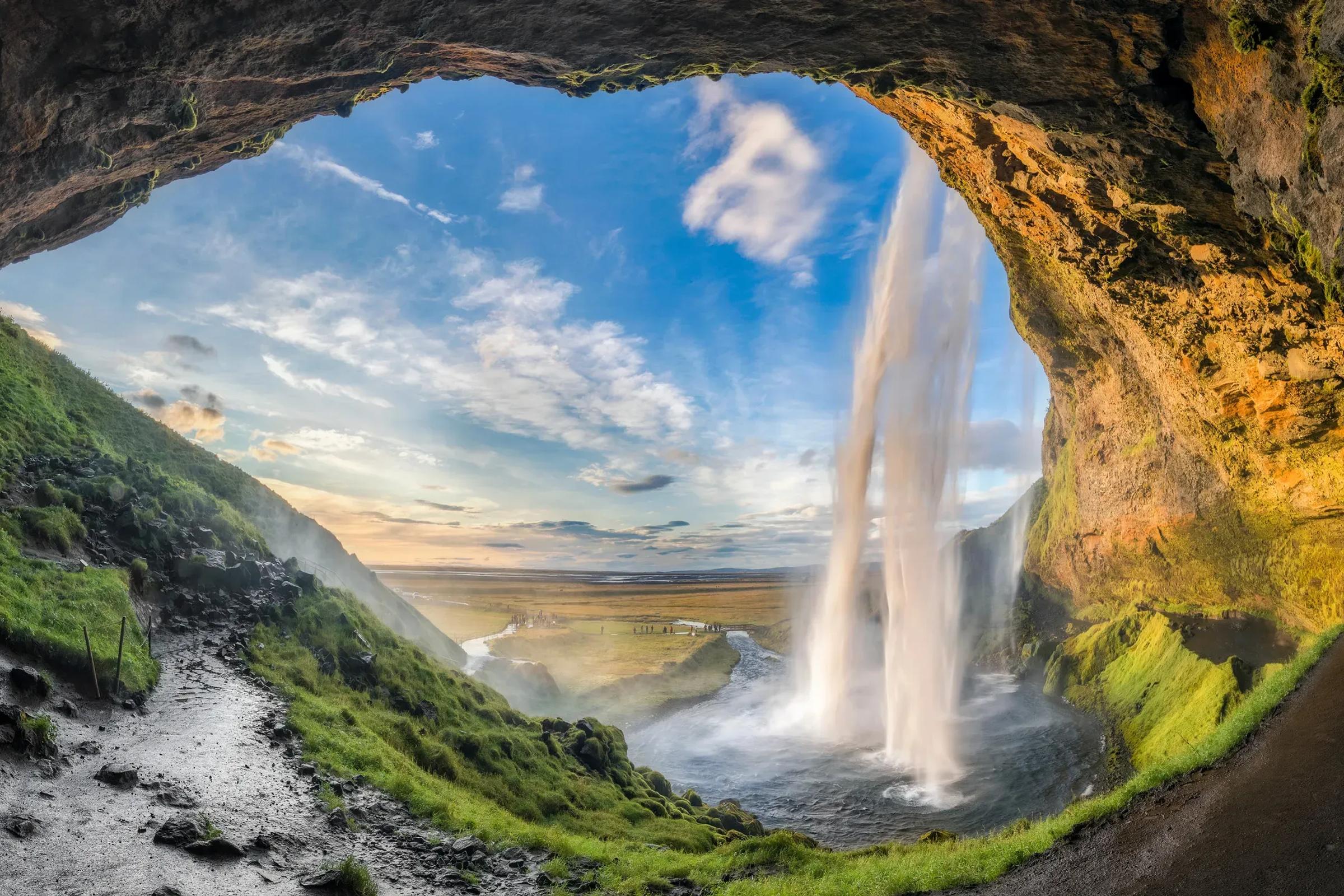 se puede ver una cascada a través de la apertura de una cueva.