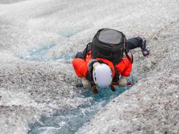 a person is climbing up a glacier with a backpack .