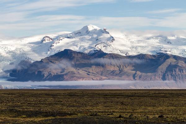 a snowy mountain in the distance with a field in the foreground .