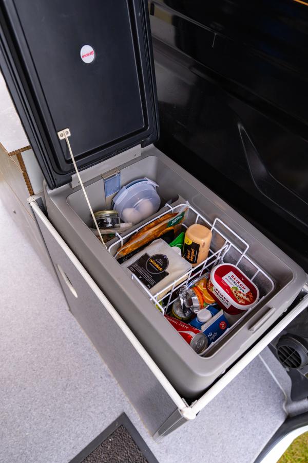 Open cool box with a wire basket of food in a 5 person large camper