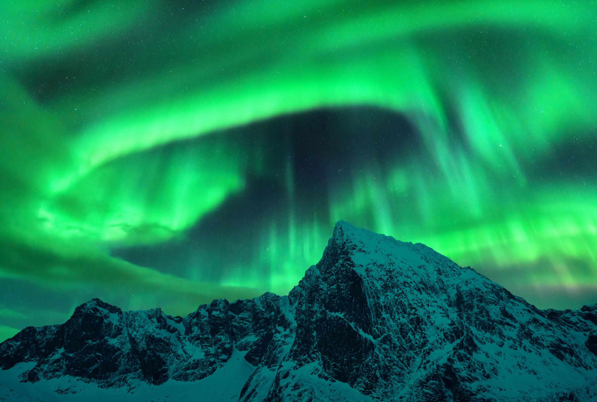 A view of Iceland in January with snow-covered mountains in iceland's south coast with aurora in the sky during cold temperatures