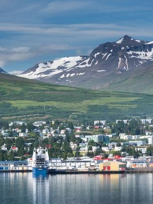 a large ship is docked in a harbor with mountains in the background .