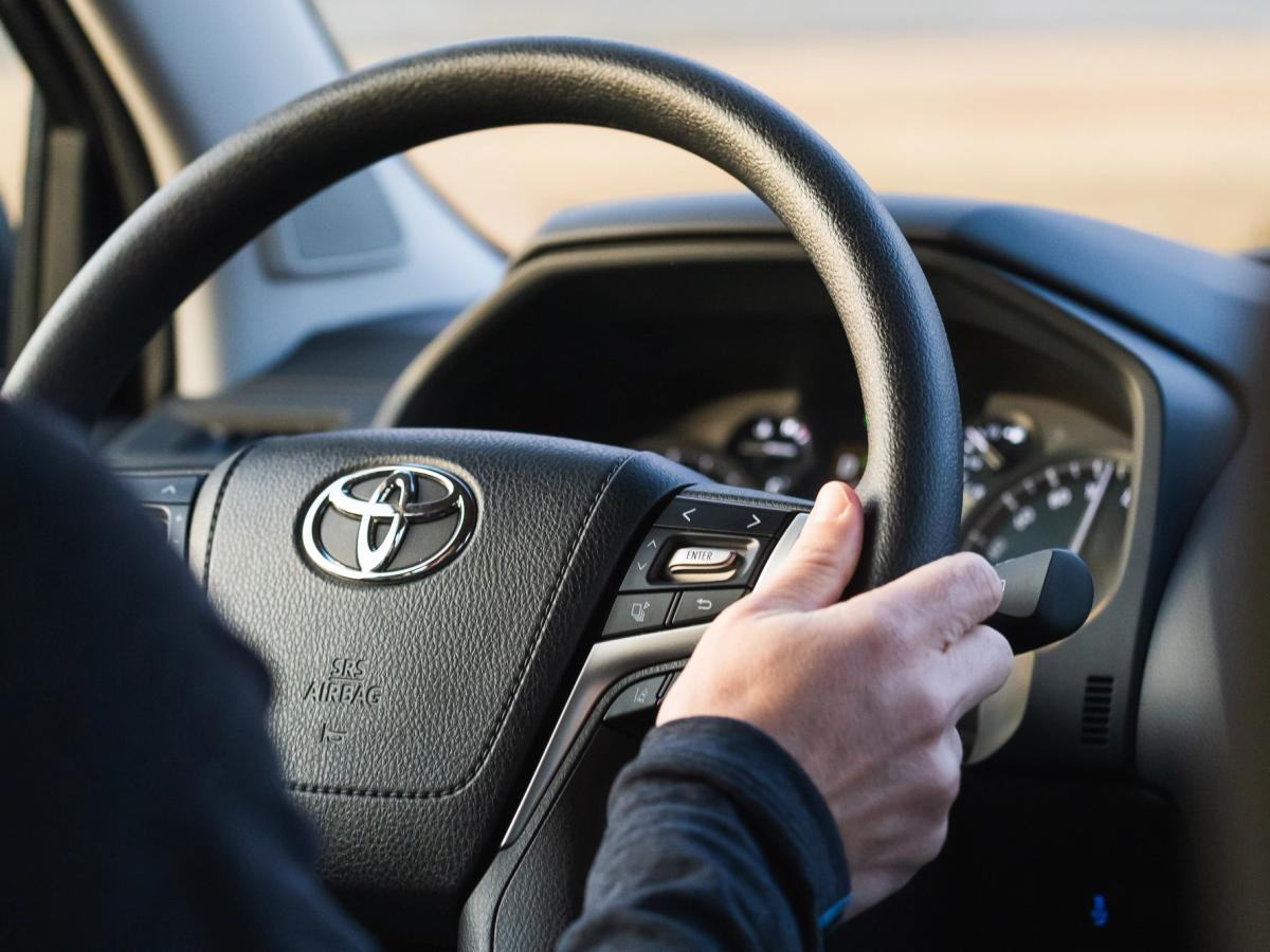 Land-Cruiser-Lenkrad Toyota-Land-Cruiser-Lenkrad mit der Hand des Fahrers am Lenkradkranz und Bedientasten