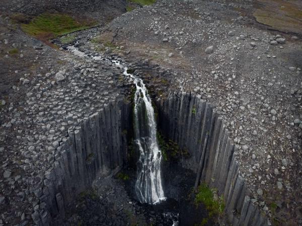an aerial view of a waterfall in the middle of a rocky area .