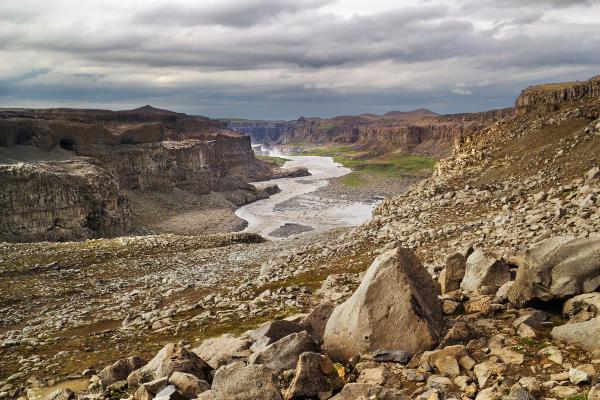 a river running through a rocky valley with mountains in the background, Jökulsárgljúfur