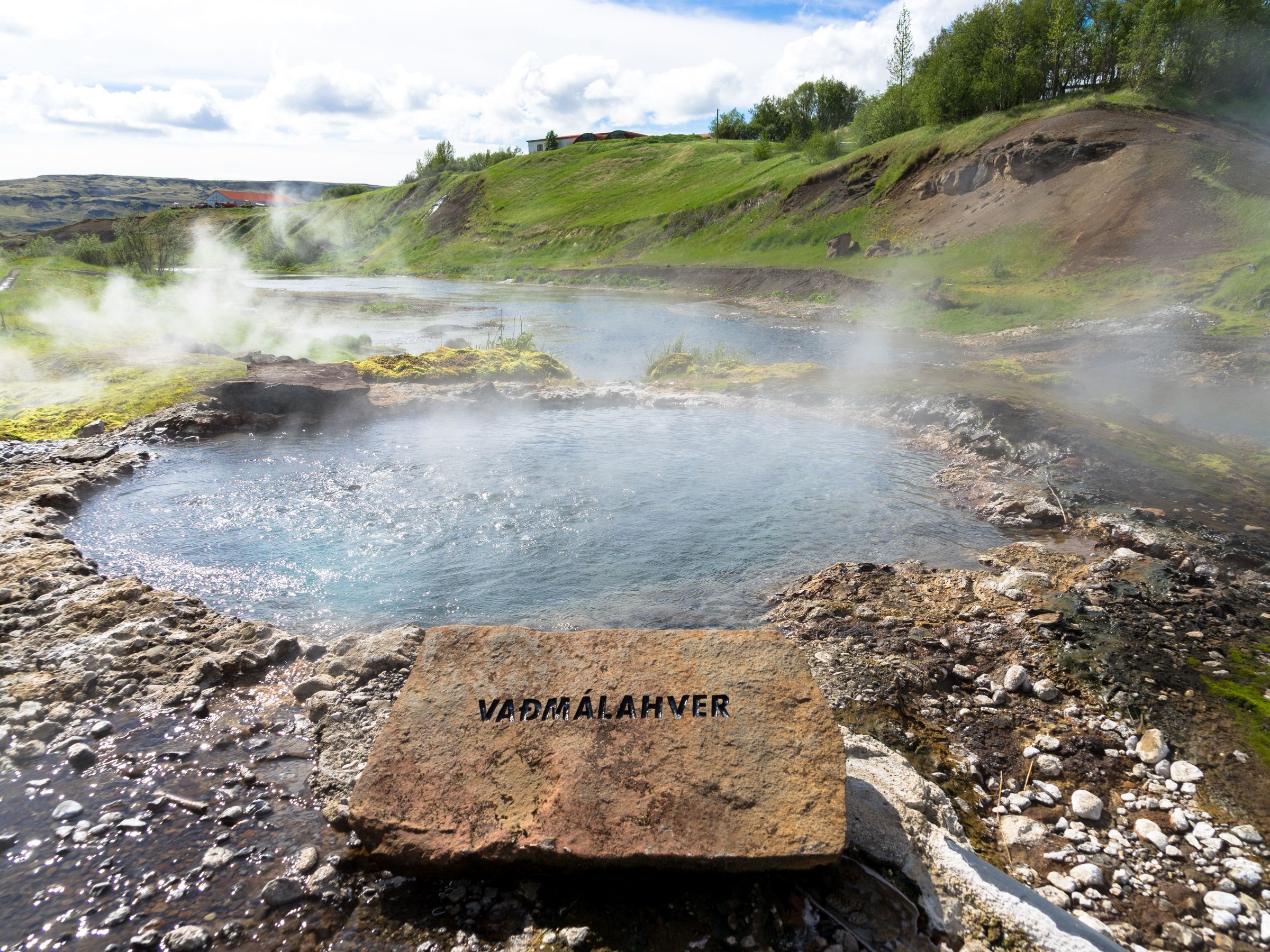 a large rock is sitting in the middle of a hot spring .