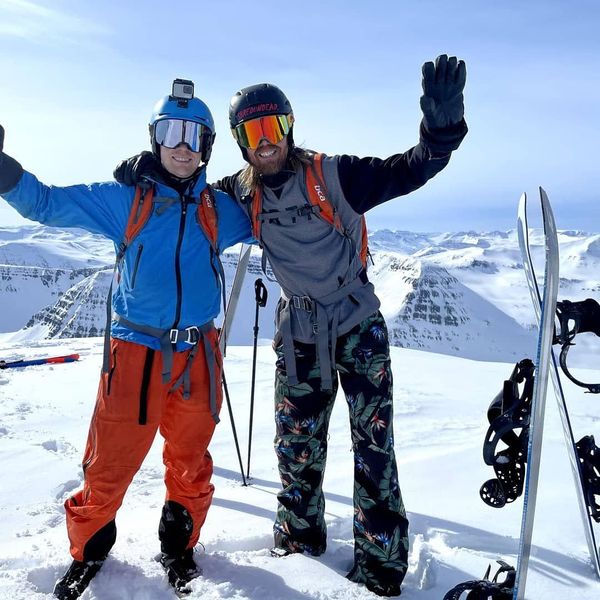 two skiers are posing for a picture on top of a snow covered mountain .