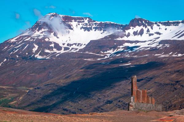 Mount Thorbjörn covered in snow with a fence in the foreground .