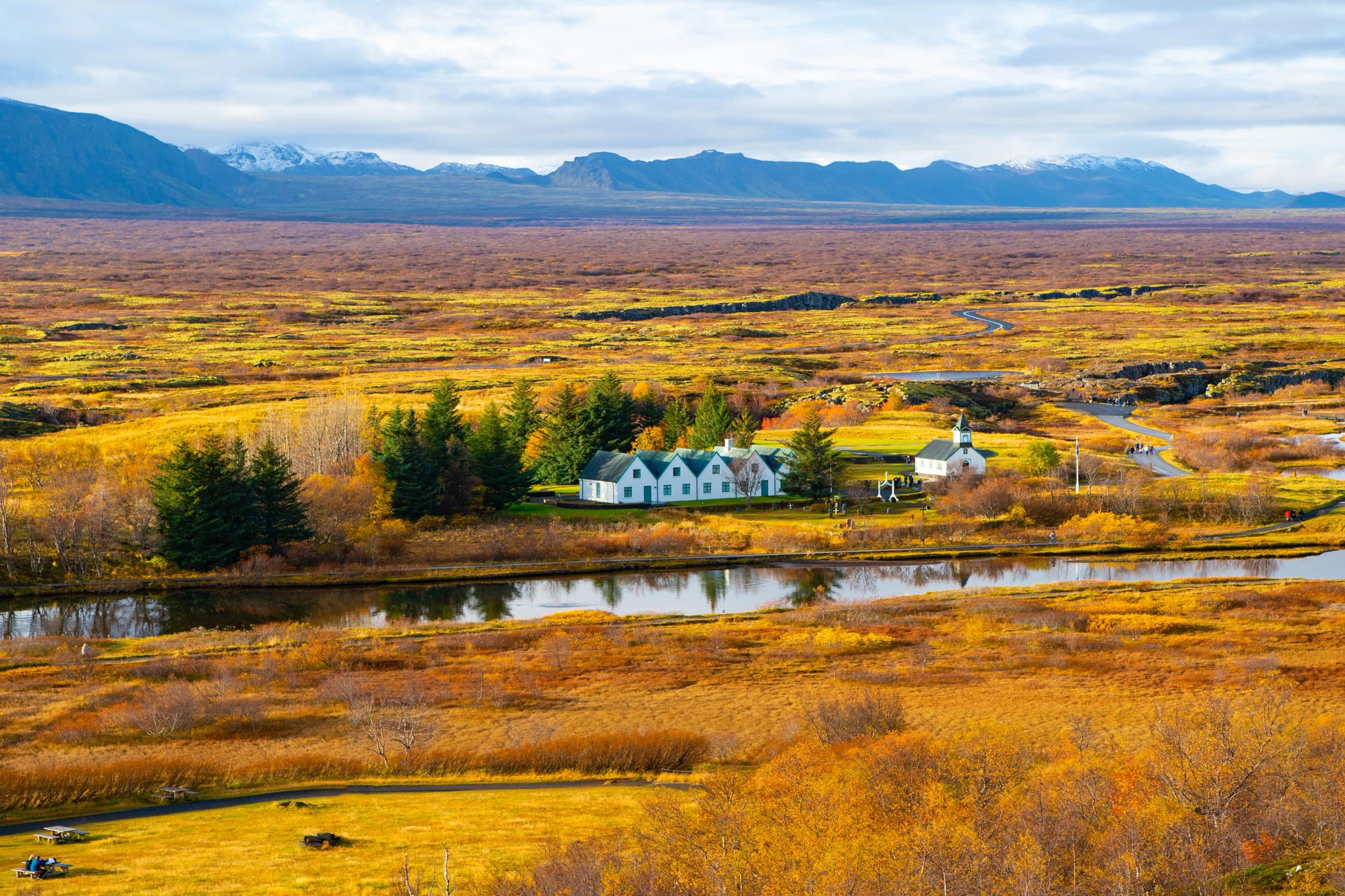 there is a house in the middle of a field next to a river .