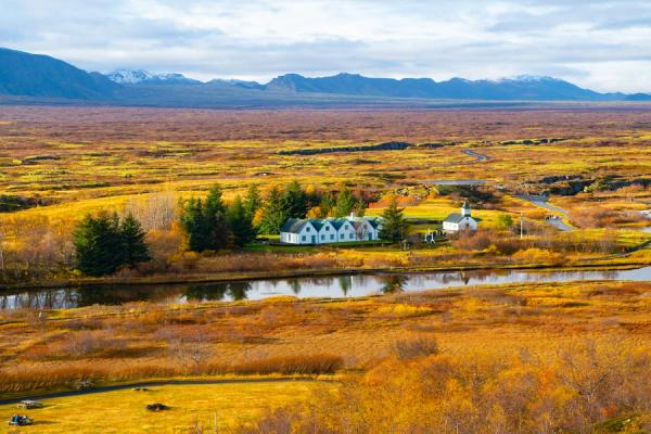 there is a house in the middle of a field next to a river .