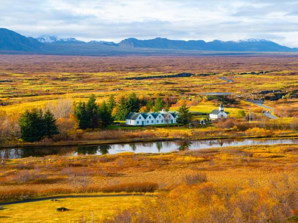 there is a house in the middle of a field next to a river .