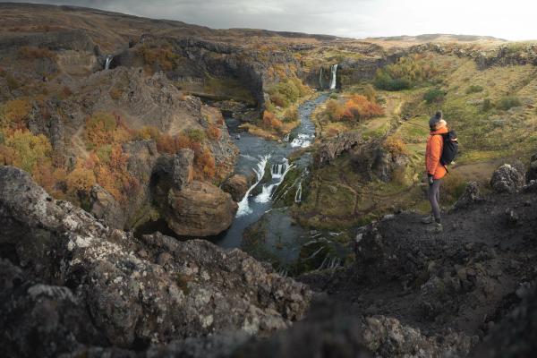 Man in front of a river on a valley with autumny colors