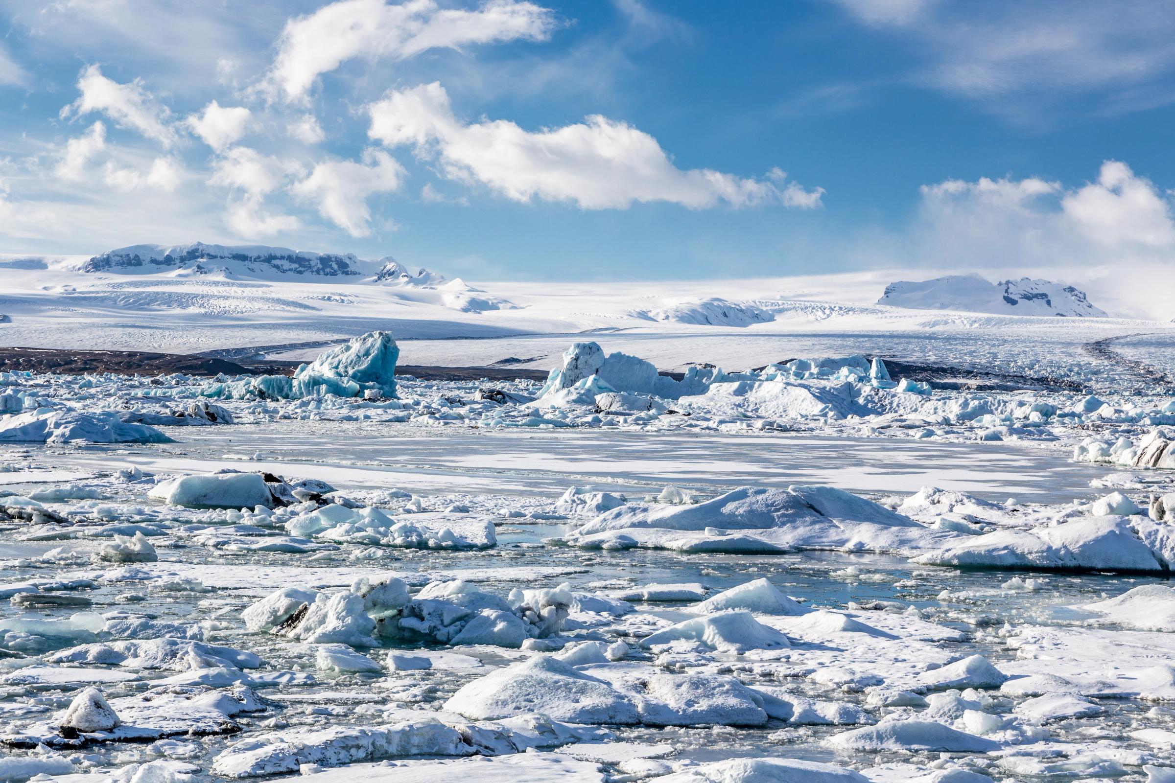 a glaciar lagoon partially frozen with a big glacier on the background