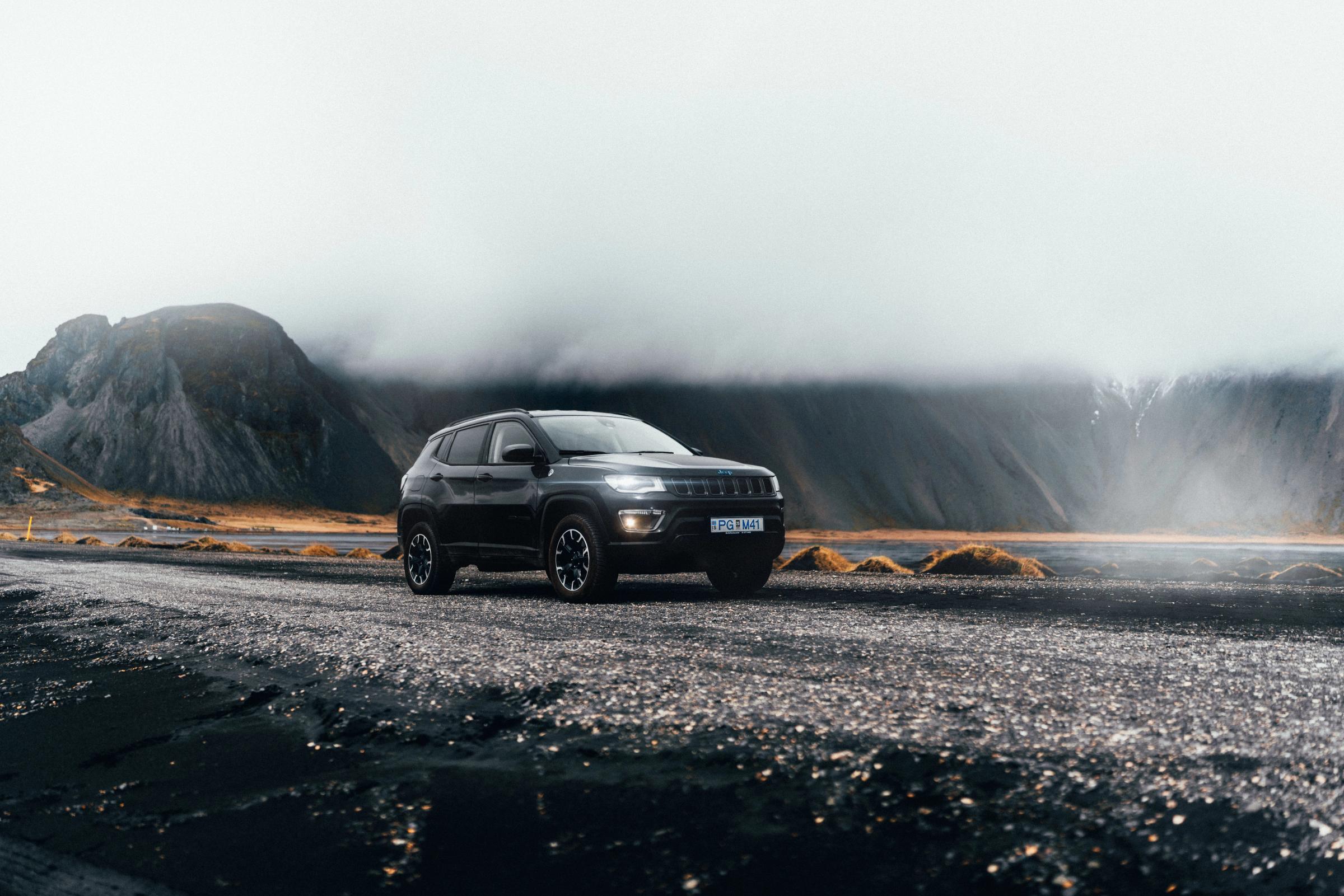 A black SUV on a dark gravel road with foggy mountains in the background.