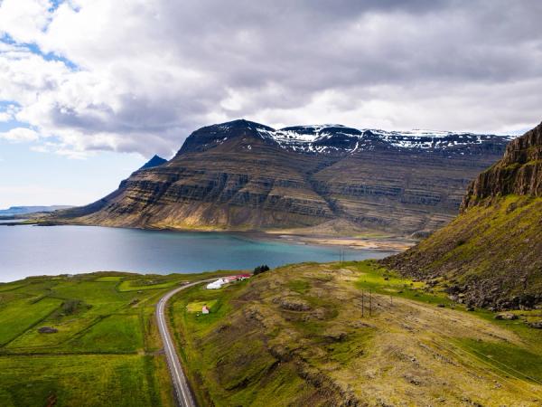 an aerial view of a road leading to a lake surrounded by mountains .