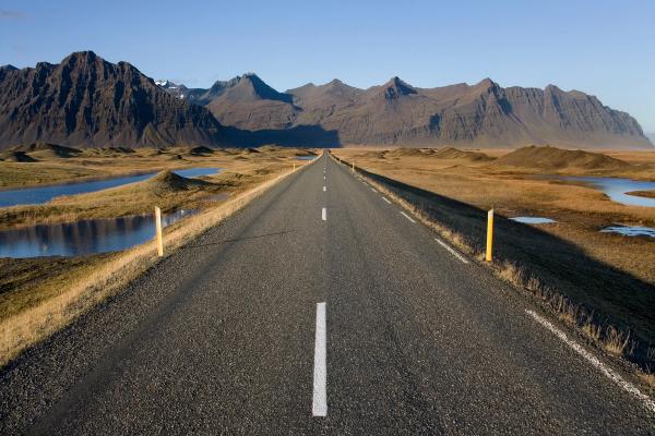 a pavemented road with mountains on the background