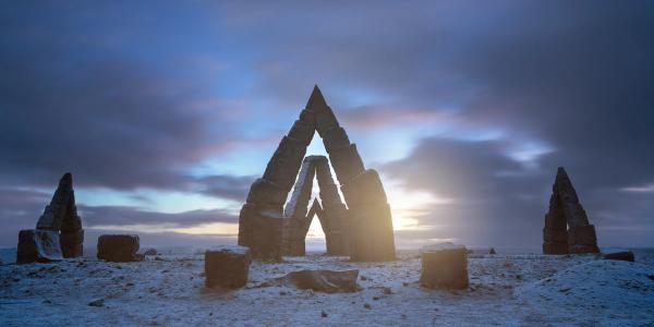 The Arctic Henge in Iceland, with light shining through its stone arches on a snowy plain.