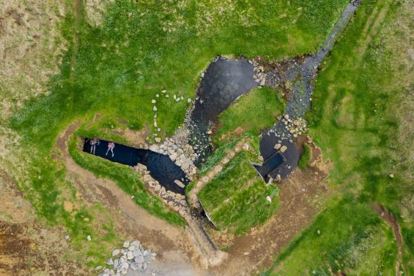 an aerial view of a river surrounded by grass and rocks .