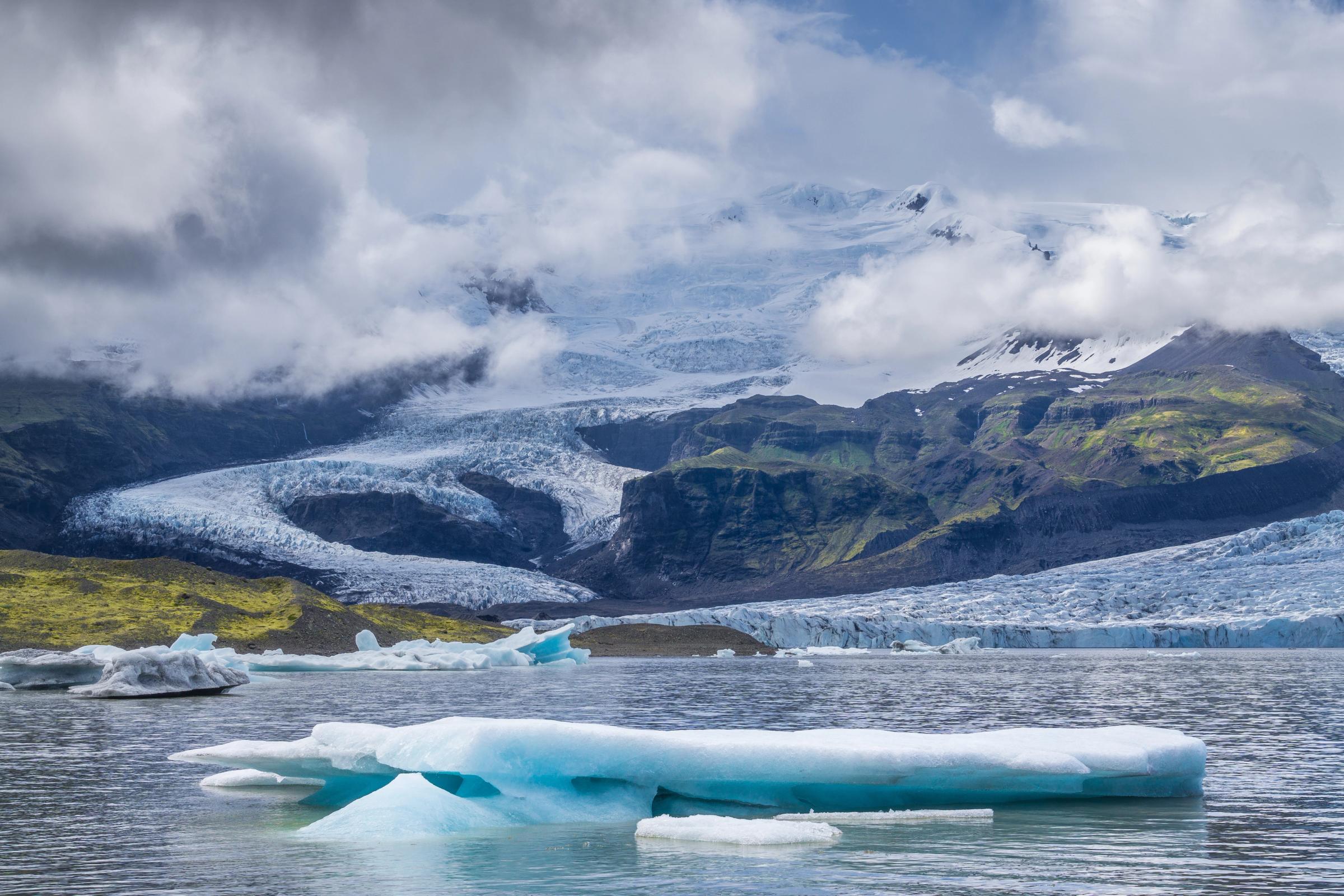 a glaciar lagoon with glacier tongue and mountain in the background