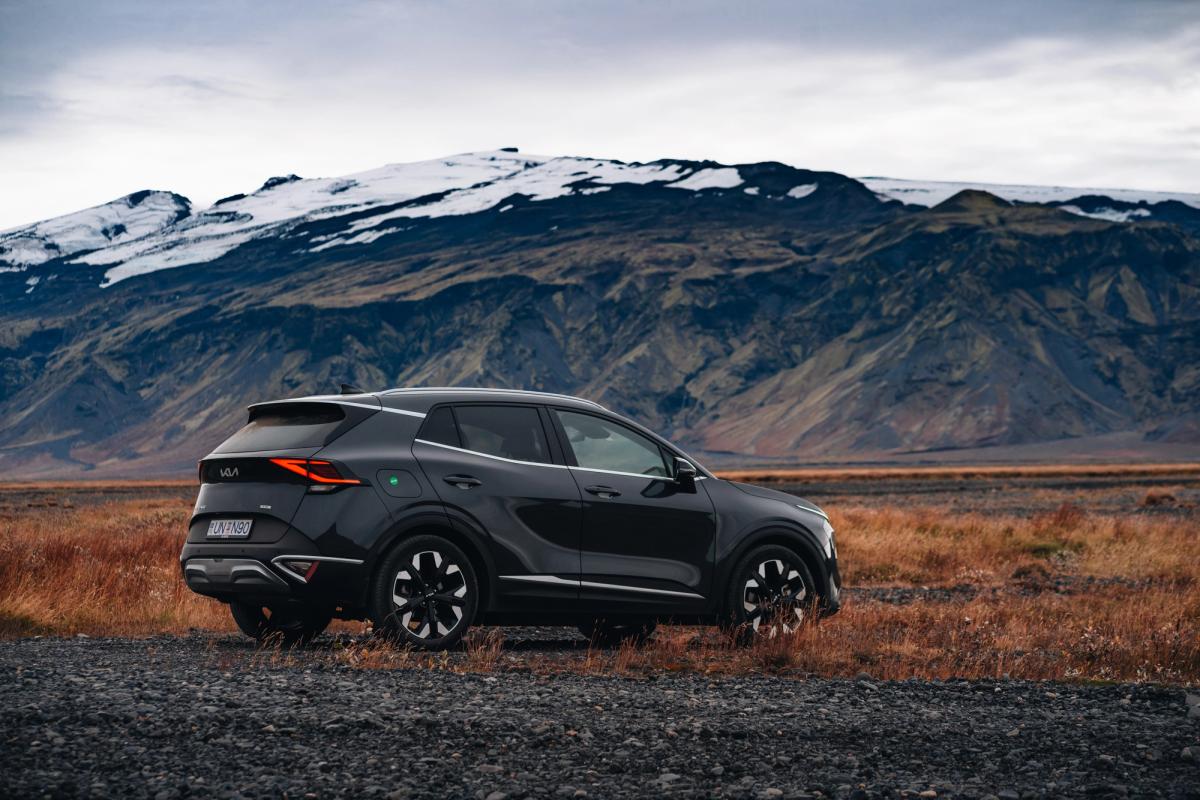 Hliðarmynd af Kia Sportage bílaleigubíl í ferðalagi um Ísland, lagt fyrir neðan fjallshrygg