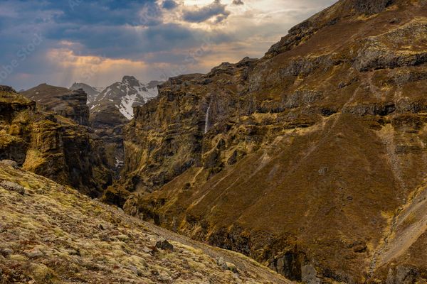 there is a waterfall in the middle of a canyon in the mountains .
