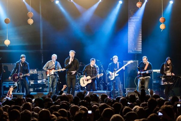 Aldrei fór ég suður - Music Festival a group of men are playing guitars on a stage in front of a crowd .