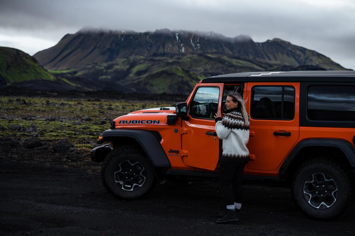 Jeep Wrangler Rubicon 4x4 侧视图，车门打开，旁边站着一人