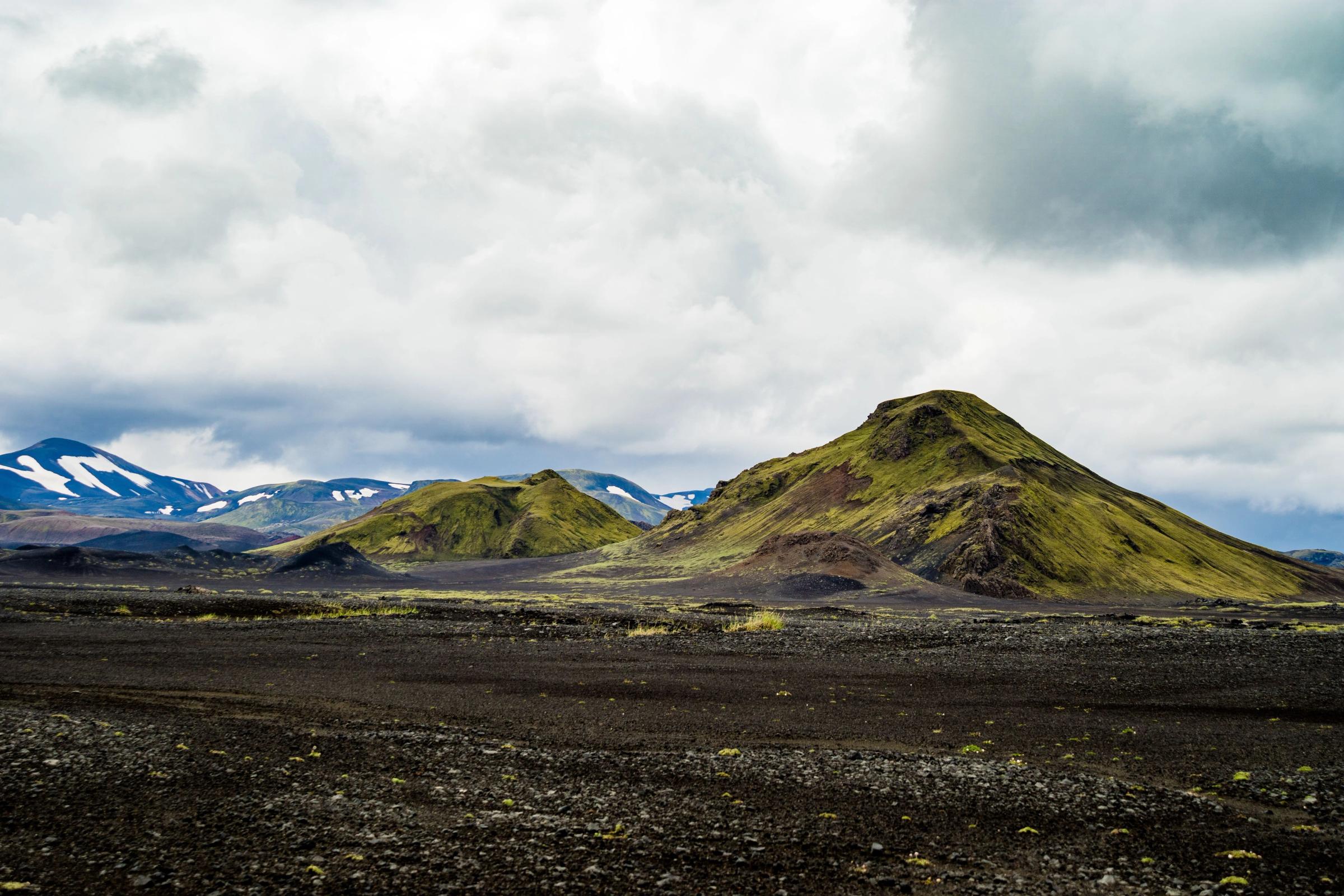 there are two mountains in the background and a dirt field in the foreground .