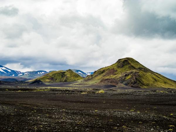 there are two mountains in the background and a dirt field in the foreground .