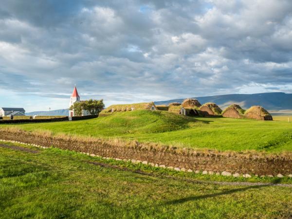 una iglesia está situada en la cima de una colina cubierta de hierba en medio de un campo .