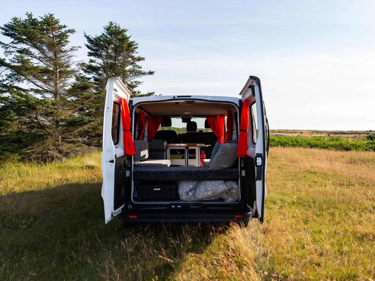 Puertas traseras para camper mediana Furgoneta cámper mediana con cortinas rojas y bolsas de almacenamiento tras las puertas traseras abiertas, alquiler de furgonetas cámper en Islandia