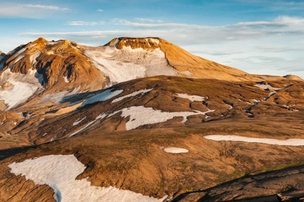 Rugged mountain landscape with scattered snow and golden light.