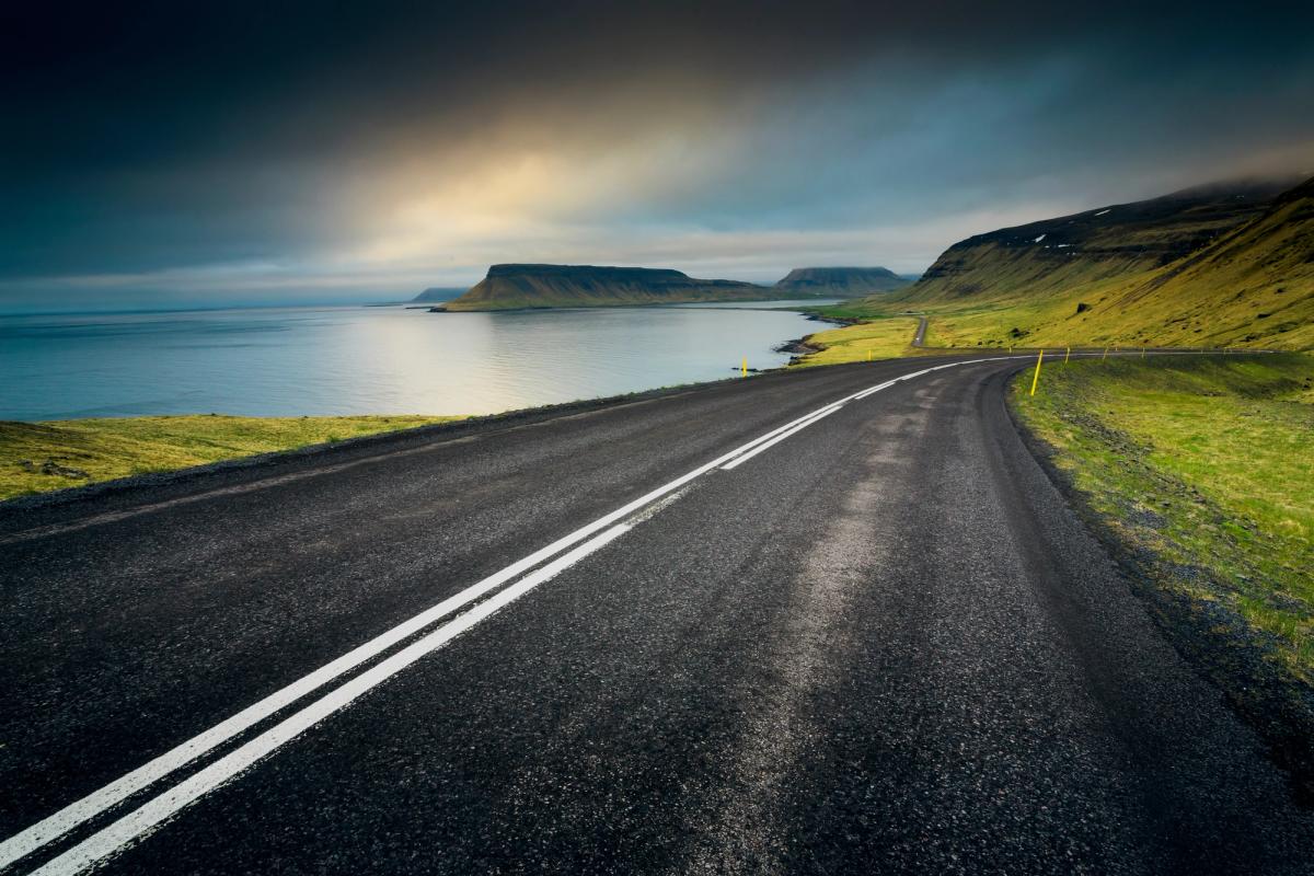 a road going through a valley next to a body of water .