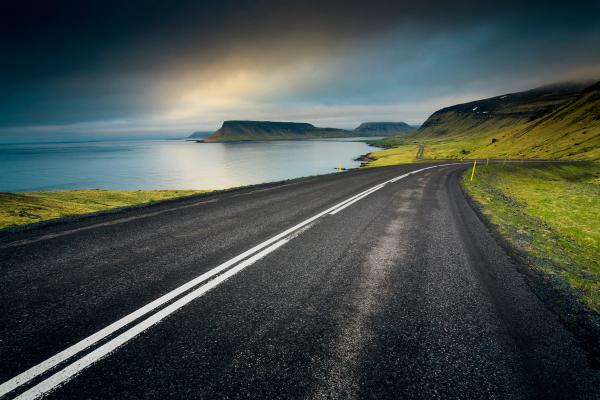a road going through a valley next to a body of water .