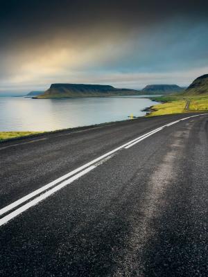 a road going through a valley next to a body of water .