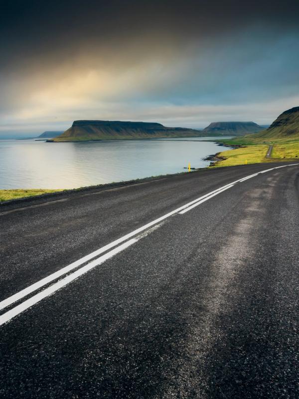 a road going through a valley next to a body of water .