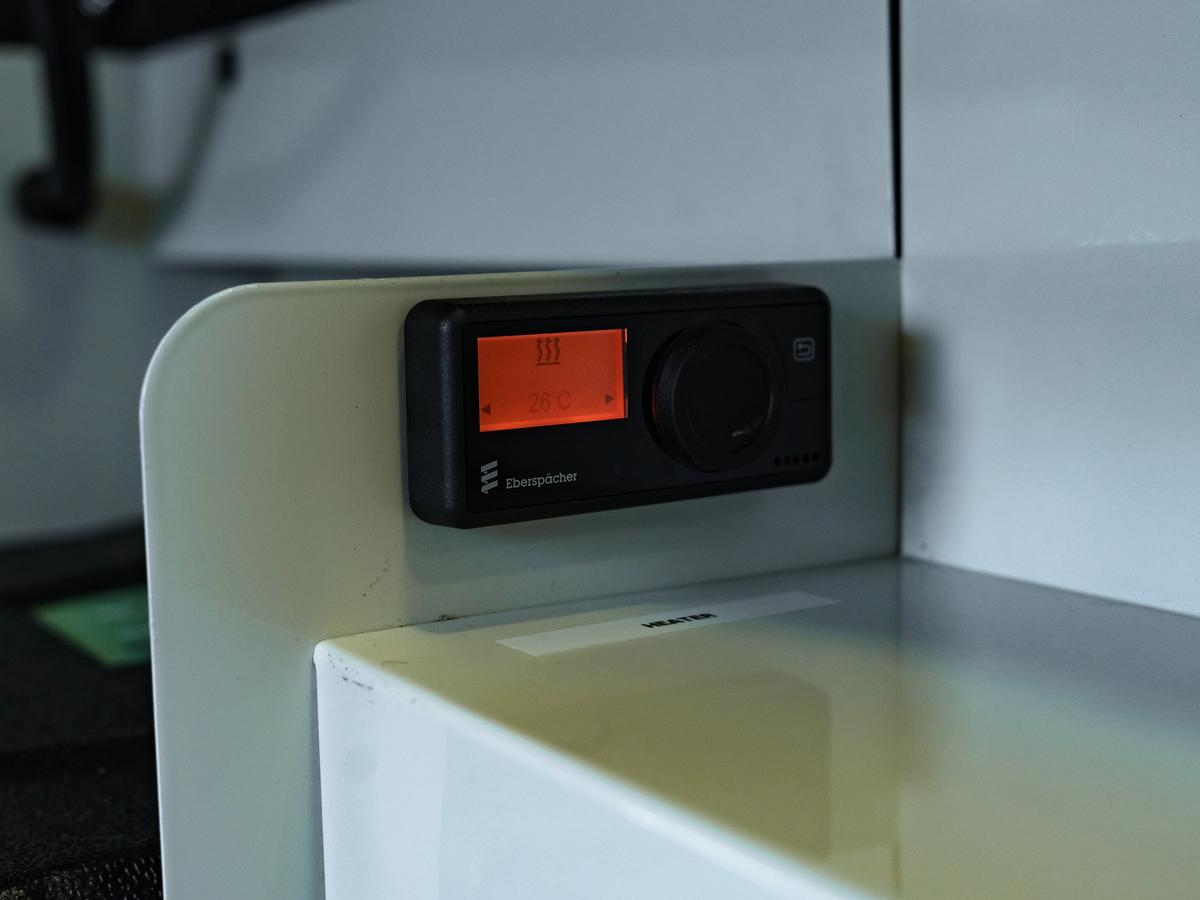 Dial de control digital Unidad de control digital de pared con pantalla naranja y mando giratorio, instalada sobre un armario blanco