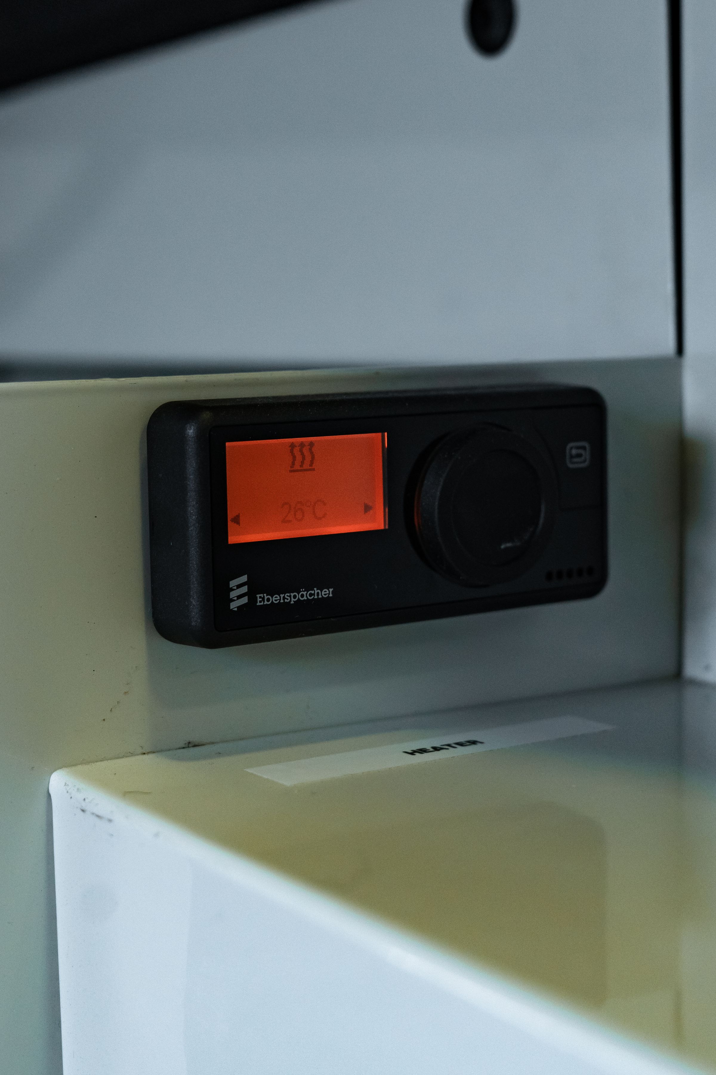 Dial de control digital Unidad de control digital de pared con pantalla naranja y mando giratorio, instalada sobre un armario blanco